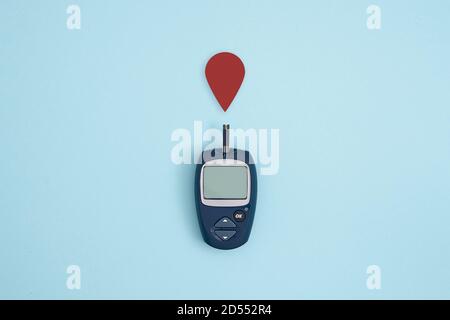 Glucometro e goccia di sangue su sfondo blu, concetto di sindrome metabolica Foto Stock