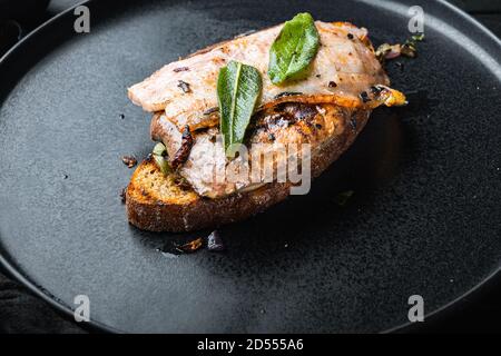 Pancetta di fegato e cipolle sul pane cotto pasto sul piatto su superficie nera Foto Stock