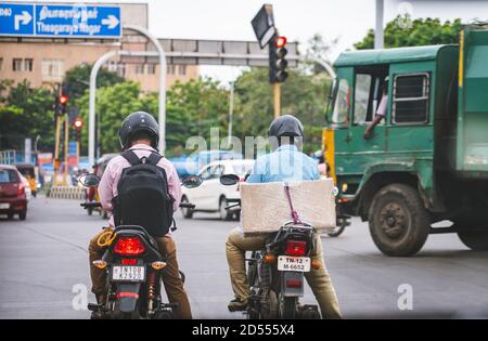 I motociclisti aspettano all'incrocio di Valluvar Kottam. I semafori rossi sono sfocati sullo sfondo Foto Stock