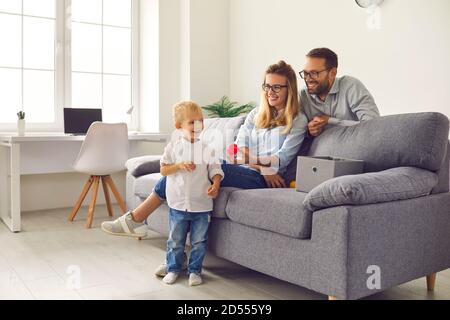 Felice giovane famiglia con un piccolo figlio sorridente che soggiorna a casa e giocare insieme giocattoli Foto Stock