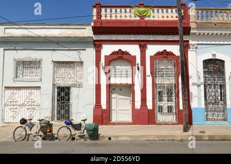 CIENFUEGOS, CUBA - 04 aprile 2018: Cienfuegos / Cuba - 3 aprile 2018: Vecchie case di colori diversi, deteriorate e povere con due biciclette parcheggiate in F Foto Stock