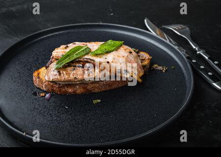 Pancetta di fegato e cipolle sul pane cotto pasto sul piatto su superficie nera Foto Stock