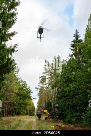 Siedenholz, Germania. 12 Ott 2020. Un escavatore carica un contenitore sospeso all'elicottero con calce di magnesio. La calce di magnesio è destinata a tamponare l'acidificazione del terreno. Credit: Philippe Schulze/dpa/Alamy Live News Foto Stock