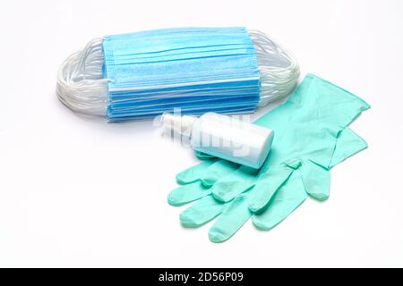 Maschera medica monouso blu, guanti in lattice di gomma e disinfettante per le mani con alcol antisettico su sfondo grigio chiaro Foto Stock