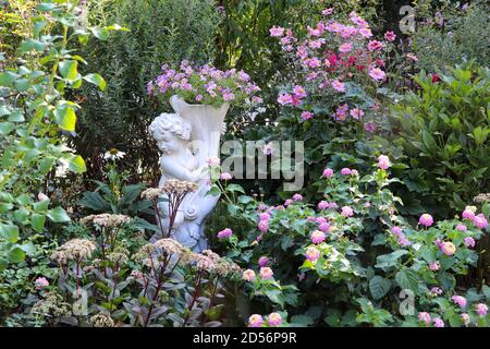 giardino estivo con putto e fiori rosa Foto Stock