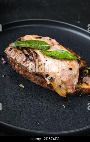 Pancetta di fegato e cipolle sul pane cotto pasto sul piatto su superficie nera Foto Stock