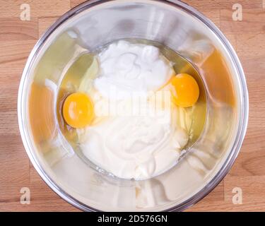 Panna acida, maionese, uova crude in una ciotola. Ingredienti per la preparazione dell'impasto per torte. Foto Stock