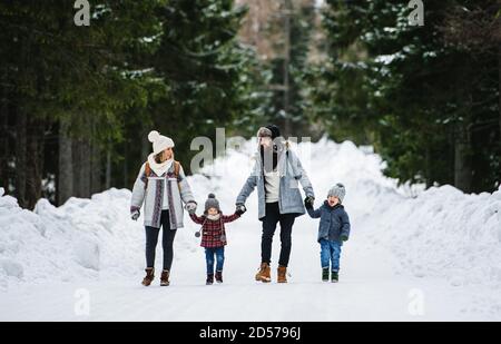 Padre e madre con due bambini piccoli nella natura invernale, camminando nella neve. Foto Stock