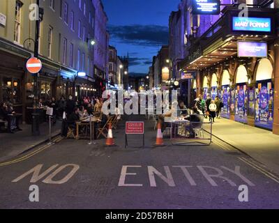 Covid-19 restrizioni temporanee segno con la folla di persone su Old Compton Street, Soho di notte. Molte strade nel centro di Londra sono state bloccate per il traffico per consentire posti a sedere all'aperto per bar e ristoranti durante la pandemia. Foto Stock