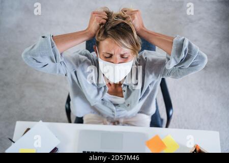 Vista dall'alto della donna al chiuso in ufficio sensazione di stress, salute mentale e concetto di coronavirus. Foto Stock