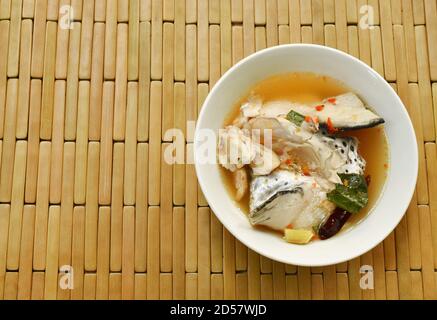 Testa di pesce di salmone piccante e funghi di paglia in Tom Yum zuppa sul recipiente Foto Stock