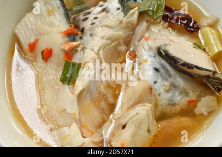 Testa di pesce di salmone piccante e funghi di paglia in Tom Yum zuppa sul recipiente Foto Stock