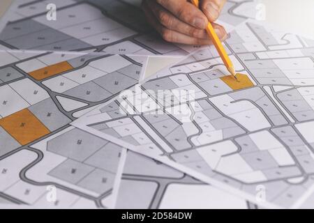 mano con matita sulla mappa catastale - scegliere e acquistare un terreno edificabile per la costruzione di una casa Foto Stock