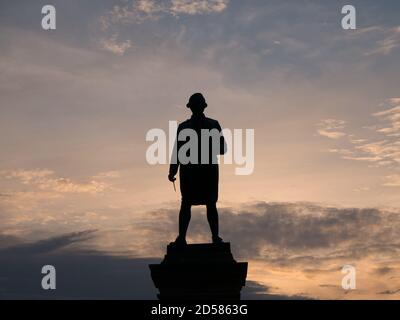 La statua in bronzo del capitano James Cook a Whitby, nel Nord Yorkshire, nel Regno Unito, si stagliò contro il tramonto al tramonto in una serata estiva successiva Foto Stock