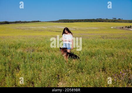 Bella donna dresss Pastore tedesco su una passeggiata in un campo Foto Stock