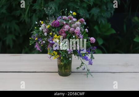 Luminoso bouquet estivo di fiori selvatici sul tavolo all'aperto Foto Stock