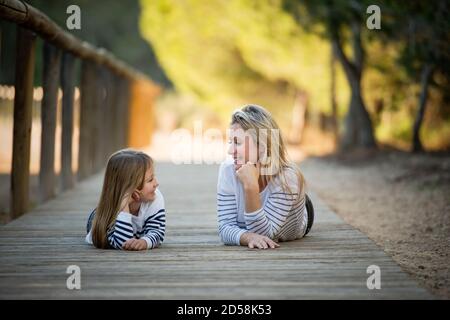 Felice madre e figlia che giacciono su un sentiero nel parco, Spagna Foto Stock