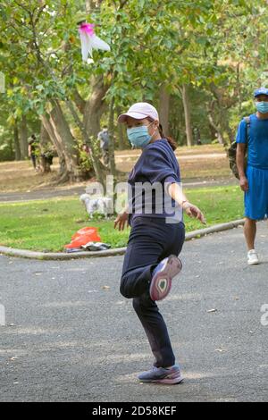 Una donna acrobatica cinese americana che gioca a Jianzi in un parco a Queens, New York City. Foto Stock