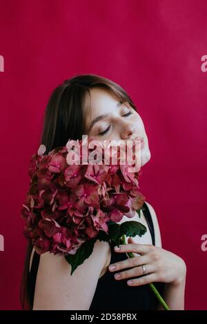 Ritratto di una giovane donna che tiene un hydrangea Foto Stock