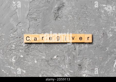 Il caregiver parola scritta sul blocco di legno. Il caregiver testo sul tavolo, concetto. Foto Stock