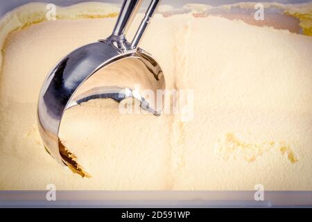 Primo piano di gelato alla vaniglia che viene ballato da una paletta meccanica. Foto Stock
