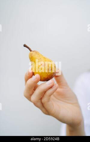 Primo piano della mano di una donna che tiene una pera Foto Stock