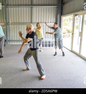 Gruppo di anziani nella classe Tai Chi che si esercitano in uno stile di vita attivo di pensione. Benefici per la salute mentale e fisica dell'esercizio fisico e del fitness negli anziani Foto Stock