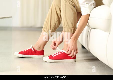 Vista laterale ritratto di una donna mani legando scarpe di sneakers a casa Foto Stock