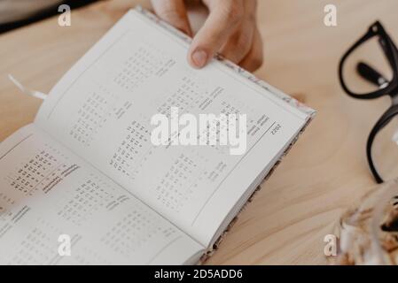 un uomo seduto a una scrivania progetta l'anno 2021 su un diario aperto con gli occhiali al suo fianco Foto Stock