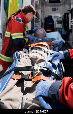 Messa a fuoco selettiva di paramedici in piedi vicino al paziente sulla barella e. ambulanza automatica Foto Stock