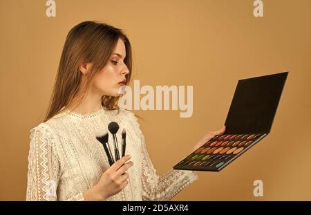 Strumenti professionali. Concetto di artista di trucco. Ottimo. Negozio di articoli per il trucco. Corsi di trucco. Bella ragazza fare labbra rosa. Donna attraente che applica spazzola di trucco. Occhiali con palette luminose. Foto Stock