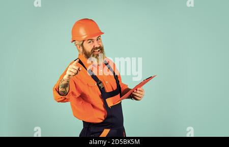 prendere appunti, industria e documenti. Lavoratore con volto felice. Ispettore controllo e ispezione edificio utilizzando checklist. appartamento in riparazione ritratto. Concetto di valore stimato della proprietà. Foto Stock