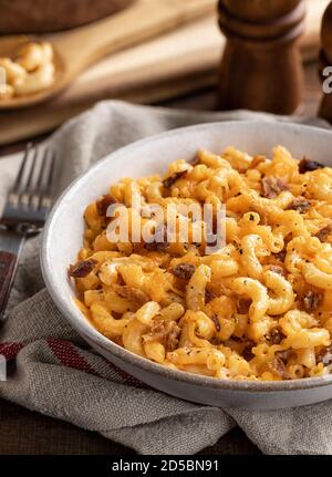 Ciotola di maccheroni e formaggio con pezzi di pancetta su a. tavolo rustico in legno Foto Stock