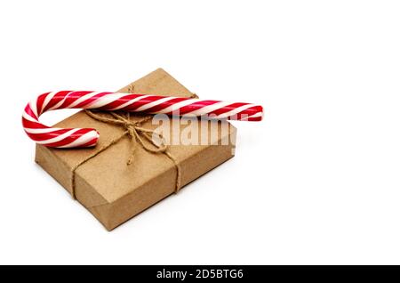 Scatola regalo di Natale avvolta in carta kraft legata con spago e canna caramella su uno sfondo bianco. Concetto di Natale, inverno e Capodanno Foto Stock