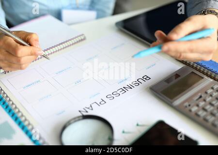 La mano tiene la penna sul tavolo si trova business plan calcolatrice lente d'ingrandimento Foto Stock