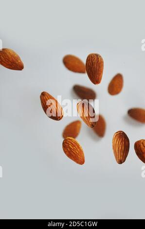 le mandorle volano su uno sfondo bianco. Composizione di mandorle piatte su fondo bianco. Concetti di decorazione, alimentazione sana e cibo Foto Stock