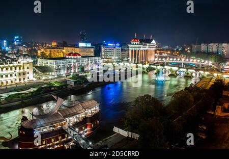 Città di Skopje capitale della Macedonia di notte e il fiume Vardar scorre sotto i ponti. Foto Stock