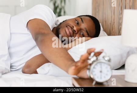 Wellslept Black Man disattivare sveglia svegliarsi in camera da letto Foto Stock