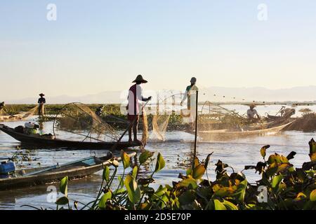 Pescatori locali birmani in piedi su piccole imbarcazioni che utilizzano reti da pesca a Inle Lake, Shan state, Myanmar Foto Stock