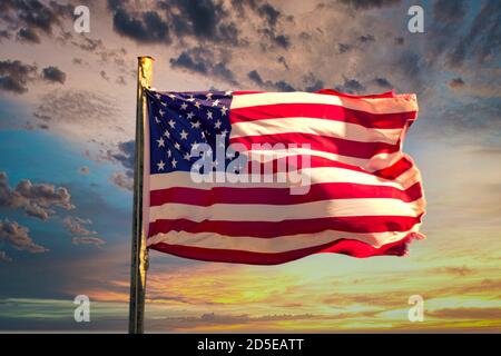 Bandiera americana che sventola orgogliosamente contro un cielo colorato al tramonto con spettacolari formazioni nuvolose Foto Stock