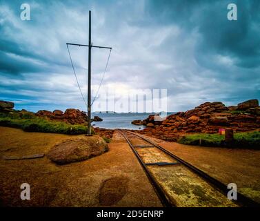 Le vie conducono giù al mare presso la stazione di salvataggio al francese Breton porto di pesca di Ploumanach. Bretagne. Francia Foto Stock