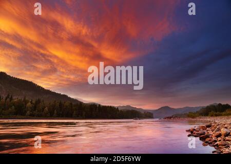Mountain landscape with river and colorful sky Foto Stock