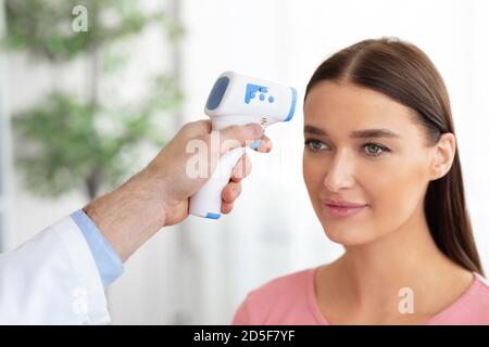 Controllo medico della temperatura del paziente mediante termometro a infrarossi Foto Stock