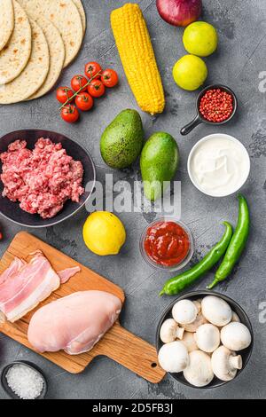 Ingredienti Taco cucina fatta in casa con verdure e pollo e carne di maiale su sfondo grigio vista dall'alto. Foto Stock