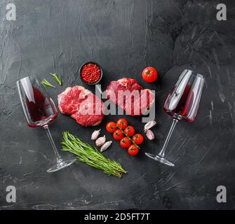 Tagli di manzo crudi con erbe, ingredienti per cena per due con bistecche e vino rosso vista dall'alto, grande spazio per il testo. Foto Stock