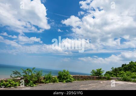 Vista spettacolare sulla spiaggia di mare e sul cielo blu dalla cima di una strada di montagna. Foto Stock