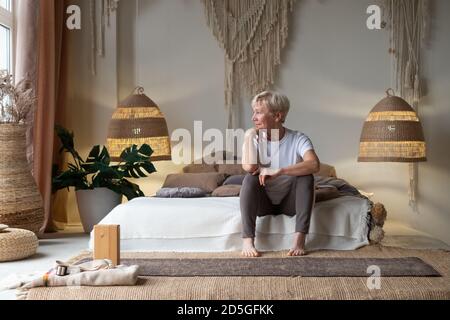 Ritratto di donna anziana a letto dopo lo yoga e guardare alla finestra Foto Stock