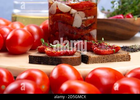 Pomodori secchi fatti in casa con olio d'oliva in un vaso di vetro. Sandwich con pane nero e pomodori secchi Foto Stock