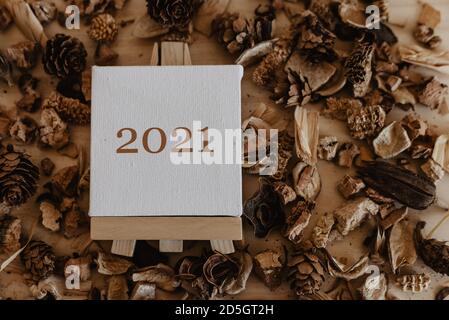 2021 scritto in marrone sulla tela di un cavalletto con frutti marroni secchi e fiori intorno ad esso. Foto Stock
