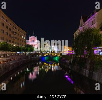 Una foto panoramica di Lubiana e dei margini del fiume Lubiana, centrata su Piazza Prešeren e il Ponte triplo, di notte. Foto Stock